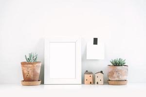 Succulents or cactus in clay pots over white background on the shelf and mock up frame photo