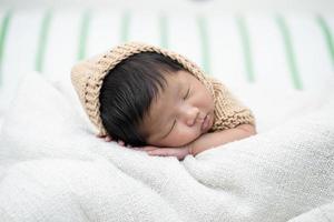 Adorable bebé recién nacido durmiendo pacíficamente sobre una manta blanca foto