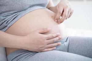 Mujer embarazada acostada y jugar con los dedos caminar sobre su barriga foto