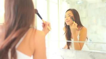 giovane donna asiatica controlla il suo viso sullo specchio? video