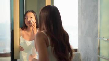 jovem mulher asiática olhando o rosto no espelho