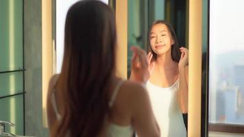 jonge aziatische vrouw controleert haar gezicht op de spiegel video