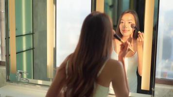 jonge aziatische vrouw controleert haar gezicht op de spiegel video