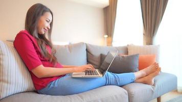 jonge Aziatische vrouw gebruikt een laptop op de bank video