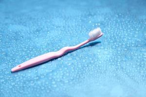 Pink toothbrush and water on blue background with a blank space for a text photo