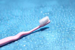 Cepillo de dientes rosa y agua sobre fondo azul con un espacio en blanco para un texto foto