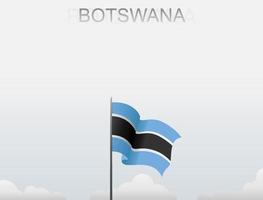 The Botswana flag is flying on a pole that stands tall under the white sky vector