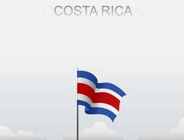 La bandera de Costa Rica ondea en un poste alto bajo el cielo blanco. vector