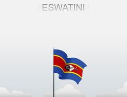 The Eswatini flag is flying on a pole that stands tall under the white sky vector