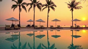 Umbrella Around Outdoor Pool with Palm Tree at Sunset video