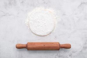 Fresh homemade yeast dough resting on white concrete background flat lay with rolling pin. photo