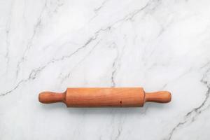 The rolling pin set up on white marble background. Baking background with the rolling with flat lay and free space for text. photo