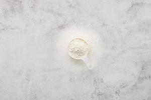 The ingredients for homemade pizza dough measuring cup wheat flour set up on white concrete background.