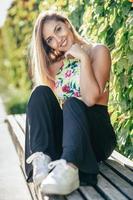 Pretty young girl sitting on urban bench photo