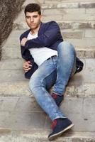 Handsome young man with blue eyes posing near a wall photo