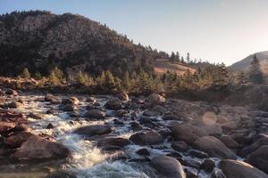 Cascada que fluye sobre piedras en el bosque de pinos en el parque nacional foto