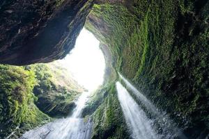 Majestic waterfall flowing on rocky cliff in tropical rainforest photo