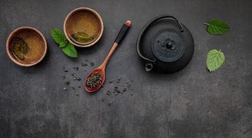 Black cast iron tea pot with herbal tea set up on dark stone background. photo