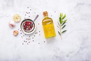 Glass bottle of olive oil and olive branch set up on white concrete background. photo