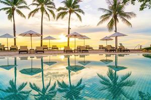 Umbrella and chair around swimming pool in hotel resort with sunrise in morning photo