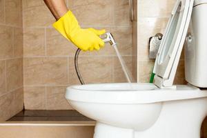 Using a hose to spray water to clean the toilet bowl. photo