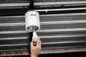 Human hand is installing an LED light bulb in a circular ceiling lamp. photo