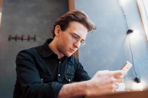 Close-up of man received good news on smart phone, Man resting in cafe and texting new mail messages, blurred background, shallow DOF photo