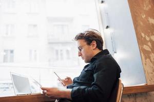 Relajado joven profesional navegando por internet en su portátil en un café