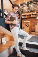 Talented young man in casual shirt drawing sketch in notebook enjoying leisure time in coffee shop.Skilled student writing down homework in notepad sitting in coworking photo