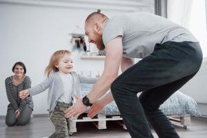 happy family is having fun at home. Mother, father and little daughter with plush toy are enjoying being together photo