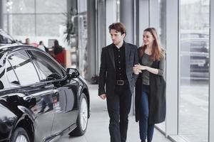 It is the one car I want. Beautiful young couple standing at the dealership choosing the car to buy photo