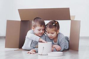 Baby brother and child sister playing in cardboard boxes in nursery
