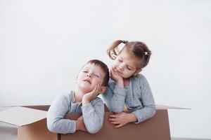 Two a little kids boy and girl playing in cardboard boxes. Concept photo. Children have fun photo