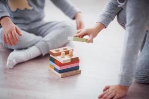 Children play with a toy designer on the floor of the children's room. Two kids playing with colorful blocks. Kindergarten educational games