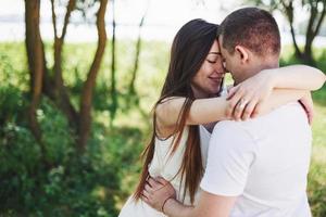 Feliz y joven pareja embarazada abrazándose en la naturaleza foto