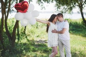 Happy and young pregnant couple hugging in nature. Romantic moments