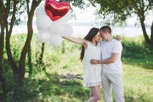 Feliz y joven pareja embarazada abrazándose en la naturaleza foto