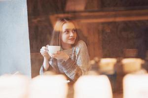 Bastante joven sentada en el café con una taza de té foto