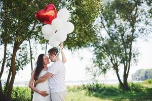 Happy and young pregnant couple hugging in nature. Romantic moments photo