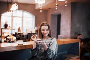 Happy smiling young woman using phone in a cafe. Beautiful girl in trendy spring colors