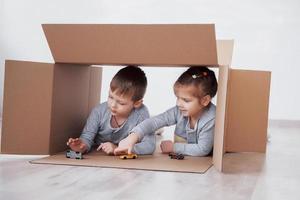 Baby brother and child sister playing in cardboard boxes in nursery photo