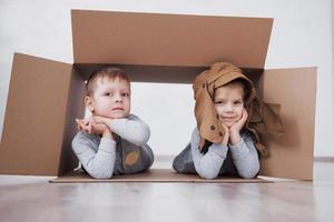 Two a little kids boy and girl playing in cardboard boxes. Concept photo. Children have fun photo