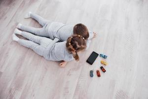 Top view. Children using digital gadgets at home. Brother and sister on pajamas watch cartoons and play games on their technology tablet photo