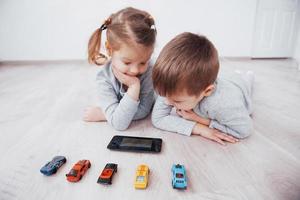 Children using digital gadgets at home. Brother and sister on pajamas watch cartoons and play games on their technology tablet photo