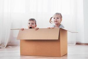 Two a little kids boy and girl playing in cardboard boxes. Concept photo. Children have fun photo