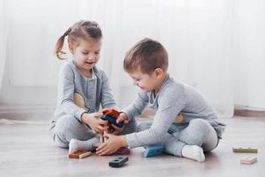 Los niños juegan con un diseñador de juguetes en el piso de la habitación de los niños. dos niños jugando con bloques de colores. juegos educativos de jardín de infantes foto