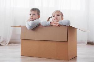 Two a little kids boy and girl playing in cardboard boxes. Concept photo. Children have fun photo