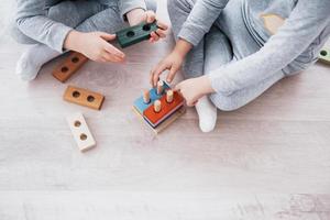 Los niños juegan con un diseñador de juguetes en el piso de la habitación de los niños. dos niños jugando con bloques de colores. juegos educativos de jardín de infantes foto