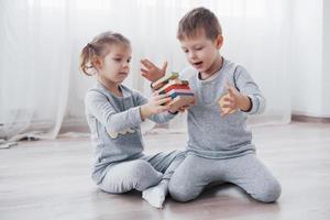 Los niños juegan con un diseñador de juguetes en el piso de la habitación de los niños. dos niños jugando con bloques de colores. juegos educativos de jardín de infantes