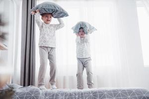 niños en pijamas suaves y cálidos jugando en la cama foto